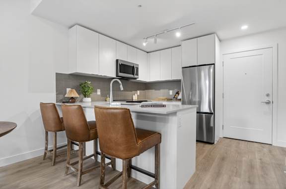 A kitchen with brown chairs and a white counter.