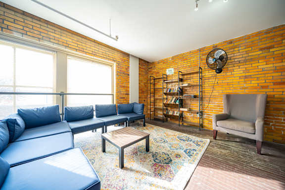 A living room with a blue couch and a brick wall.