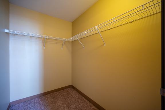 A long metal clothes hanger is on a shelf in a room.