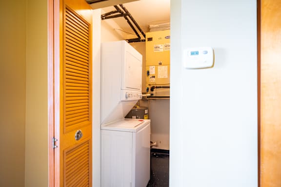 A small kitchen with a white fridge and a wooden door.