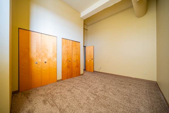 Three wooden doors in a room with carpeted floor.