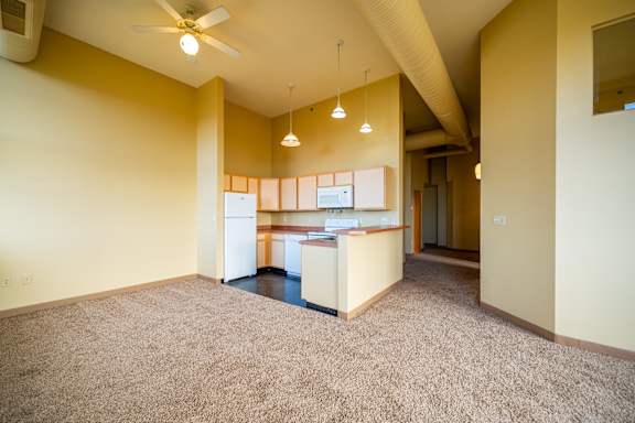 A spacious room with a carpeted floor and a ceiling fan.