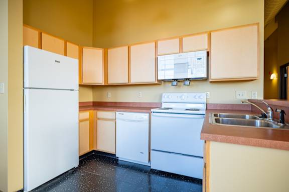 A kitchen with a white refrigerator, dishwasher, and stove.
