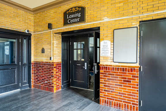 The entrance to a leasing center with a brick wall and a black door.