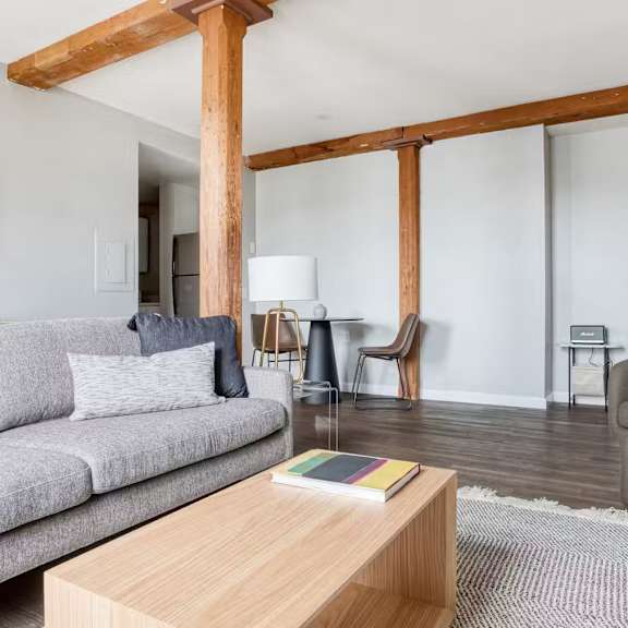 A living room with a grey couch, a wooden coffee table, and a lamp.