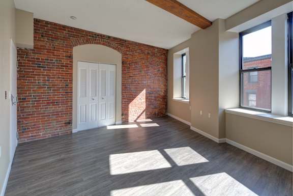 A room with a brick wall and wooden floors.