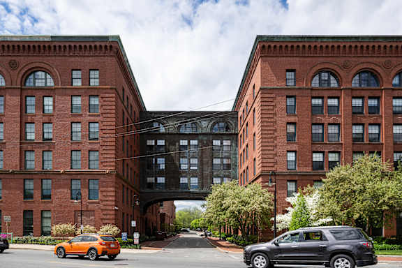 Two red brick buildings with a black car parked in front of them.