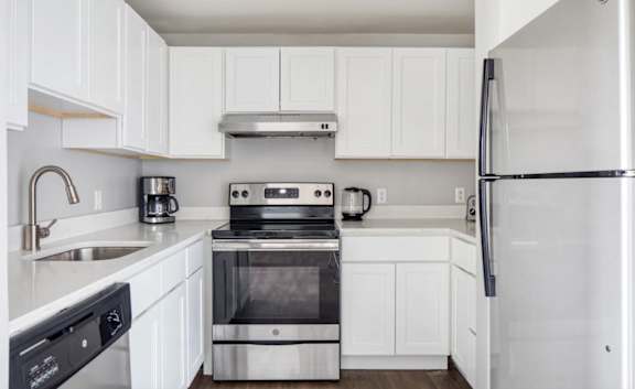 A white kitchen with a stove, oven, microwave, and refrigerator.