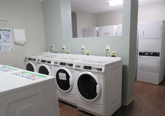 A row of white front load washing machines in a laundromat.