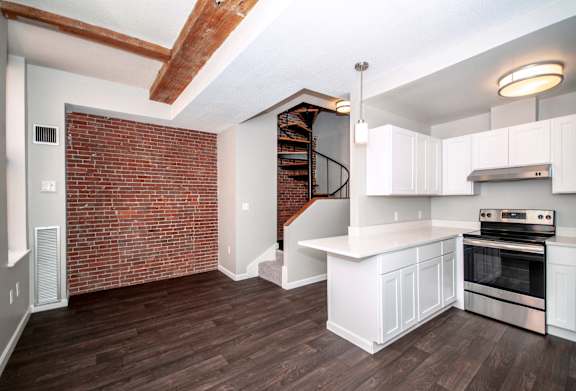 A kitchen with a brick wall and a spiral staircase.