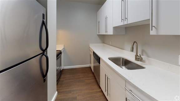 A kitchen with white cabinets and a stainless steel refrigerator.