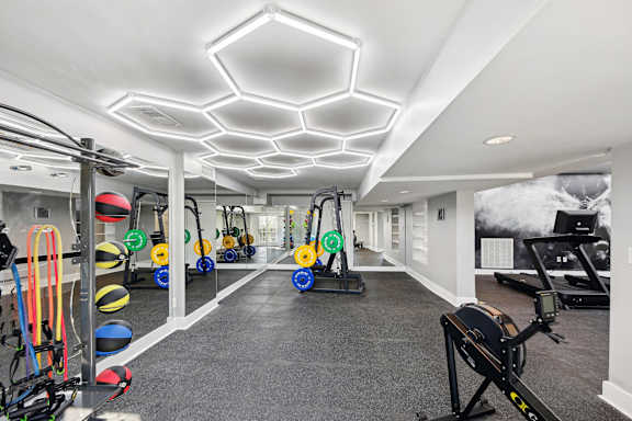 A gym with a variety of equipment including a rowing machine, a treadmill, and a stationary bike.