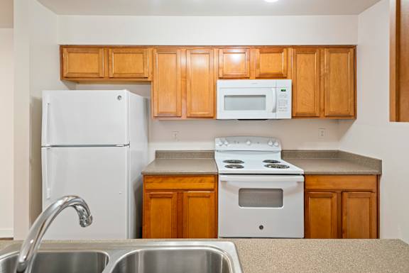 A kitchen with white appliances and wooden cabinets.