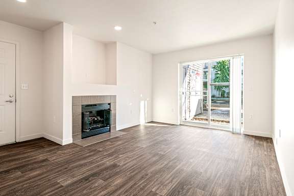 A spacious living room with a fireplace and hardwood floors.