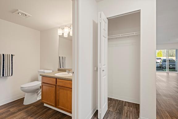 A white bathroom with a toilet, sink, and wooden floors.