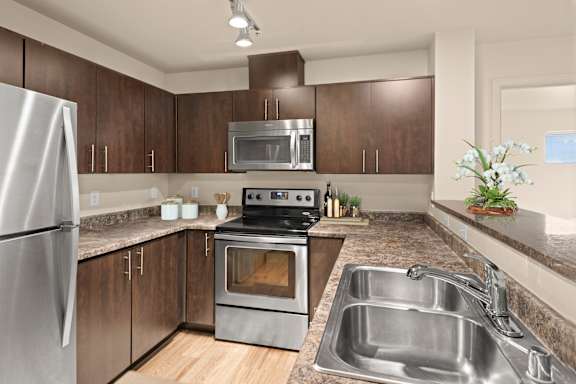 A modern kitchen with a stainless steel refrigerator, oven, and sink.