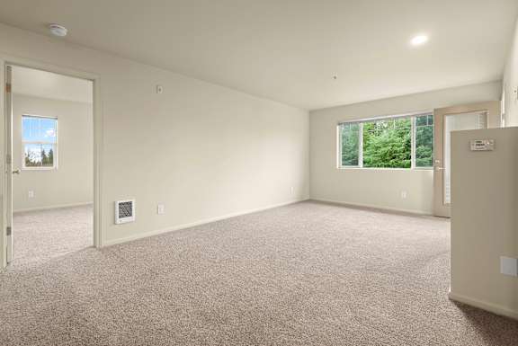 A spacious room with a carpeted floor and a window overlooking a green landscape.