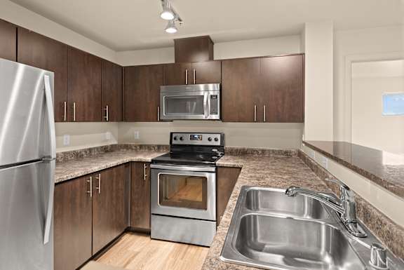 A modern kitchen with a stainless steel refrigerator, oven, and sink.