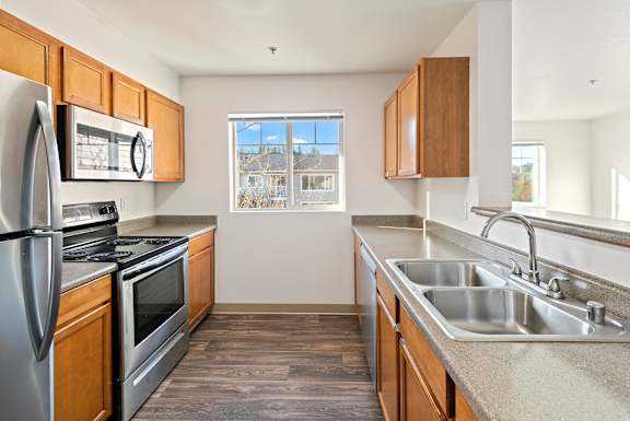 A kitchen with a stainless steel refrigerator, oven, and sink.