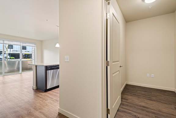 A kitchen area with a trash bin and a door.