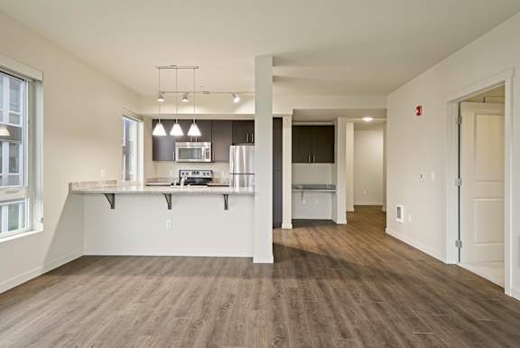 A large open room with a kitchen area and a long hallway.