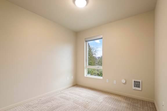 A room with a window and a carpet on the floor.