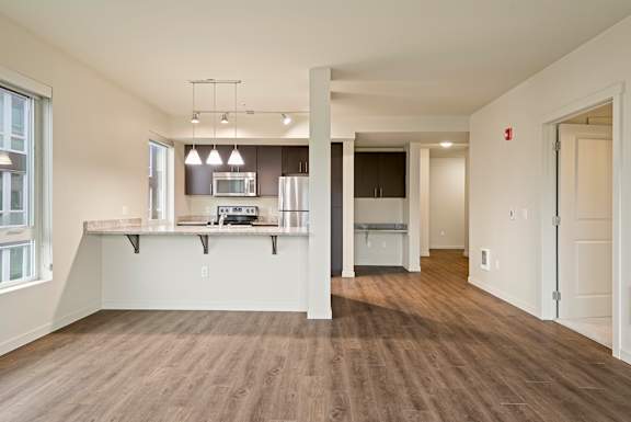 A large open room with a kitchen area and a long hallway.