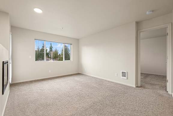 A spacious room with a large window and carpeted floor.