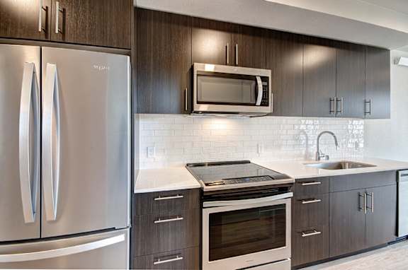 A modern kitchen with a stainless steel refrigerator and a white backsplash.