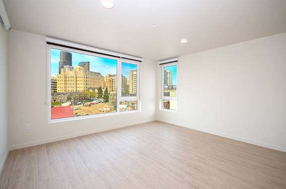 A large empty room with a view of a cityscape through the windows.