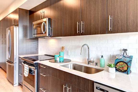 A modern kitchen with a stainless steel refrigerator and ample cabinet storage..