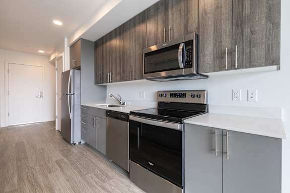 A modern kitchen with a refrigerator, oven, and microwave.