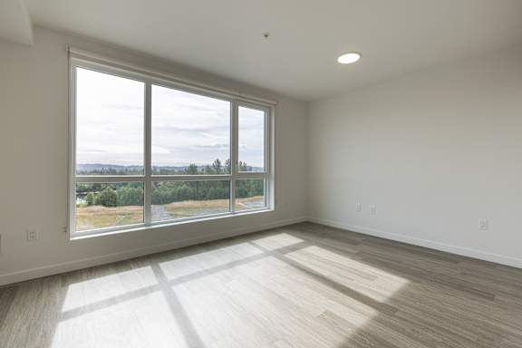 A large empty room with a view of the outdoors through a large window.