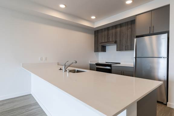 A modern kitchen with a white countertop and stainless steel appliances.