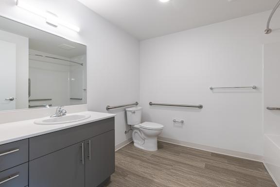 A bathroom with a sink, toilet, and grab bars.
