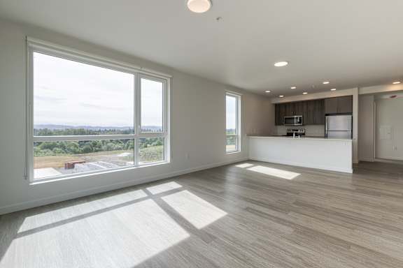 A spacious room with a large window overlooking a parking lot.