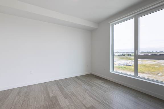 A room with a large window and wooden flooring.