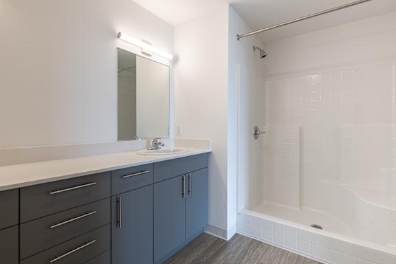 A bathroom with a white tub and a mirror above the sink.