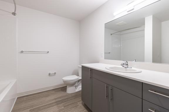 A bathroom with a toilet, sink, and mirror.