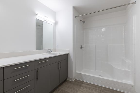 A white bathroom with a sink, mirror, and shower.