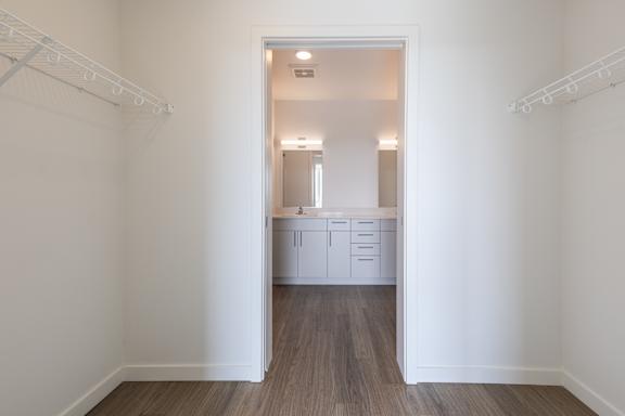 A white room with a wooden floor and a white cabinet with drawers in the doorway.