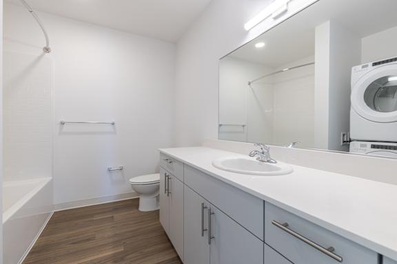A white bathroom with a toilet, sink, and mirror.