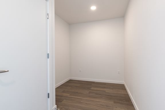 A room with a white door and a wooden floor.