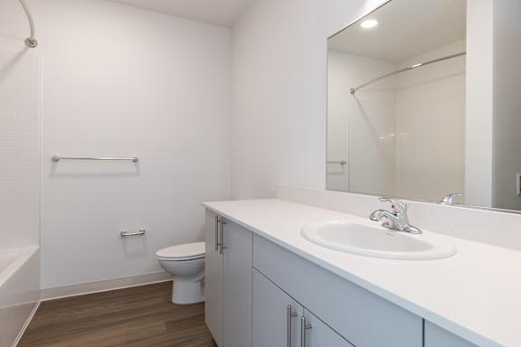 A white bathroom with a toilet, sink, and mirror.