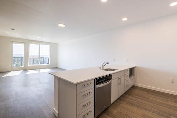 A kitchen with a sink, stove, and drawers.