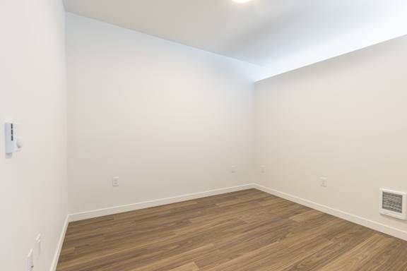 A room with wooden flooring and white walls.