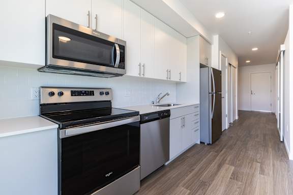 A modern kitchen with stainless steel appliances and wooden flooring.