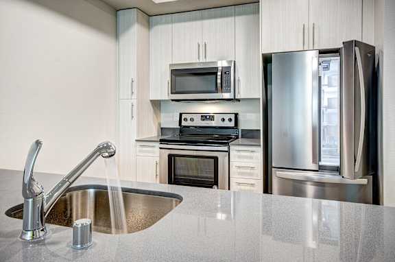 A modern kitchen with a stainless steel sink and appliances.