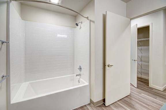A white bathroom with a walk-in shower and a door leading to another room.