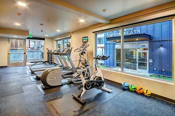 A gym with treadmills, elliptical machines, and a sign that says "Hupton Flats".